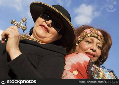 Low angle view of a mature woman holding a cross with another mature woman behind her