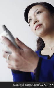 Low angle view of a mature woman holding a mobile phone thinking