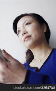 Low angle view of a mature woman holding a mobile phone thinking