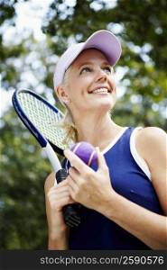 Low angle view of a mature woman holding a tennis racket and a tennis ball