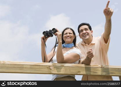 Low angle view of a mature woman holding binoculars with a mature man pointing beside her