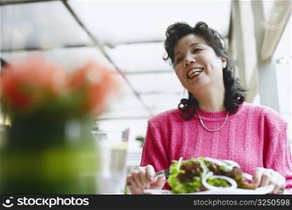 Low angle view of a mature woman seated at the table in a restaurant smiling