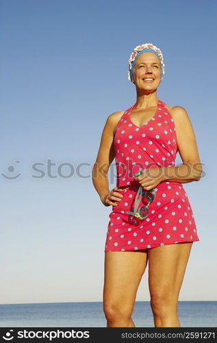 Low angle view of a mature woman standing on the beach and smiling