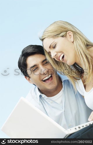 Low angle view of a mid adult couple with a laptop and smiling