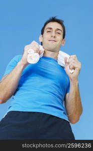 Low angle view of a mid adult man holding a towel around his neck