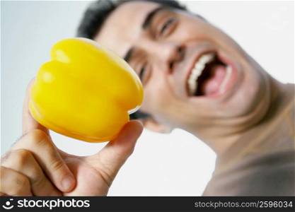 Low angle view of a mid adult man laughing and holding a yellow bell pepper