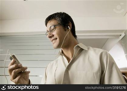 Low angle view of a mid adult man listening to an MP3 Player