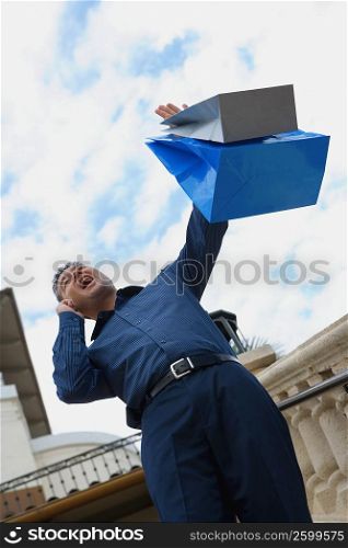 Low angle view of a mid adult man standing on steps with shopping bags