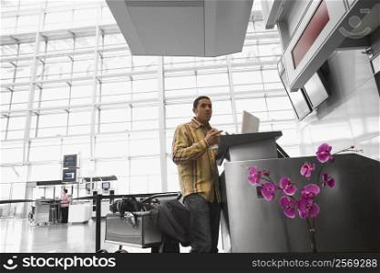 Low angle view of a mid adult man using a laptop at an airport