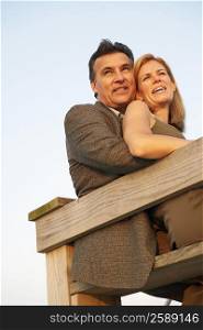 Low angle view of a mid adult woman and a mature man sitting by a railing