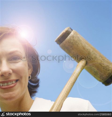 Low angle view of a mid adult woman holding a croquet mallet and smiling