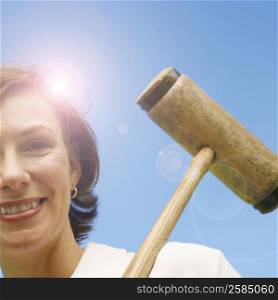 Low angle view of a mid adult woman holding a croquet mallet and smiling