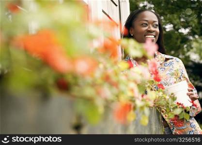 Low angle view of a mid adult woman holding a potted plant and smiling