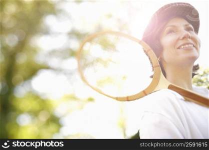 Low angle view of a mid adult woman holding a tennis racket and smiling