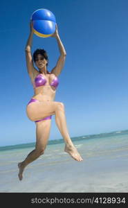 Low angle view of a mid adult woman playing with a beach ball on the beach