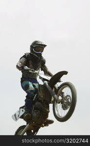 Low angle view of a motocross rider performing a jump on a motorcycle