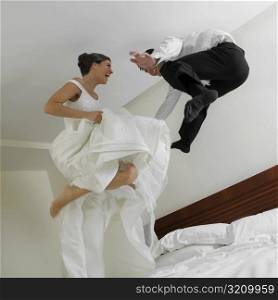 Low angle view of a newlywed couple jumping on the bed
