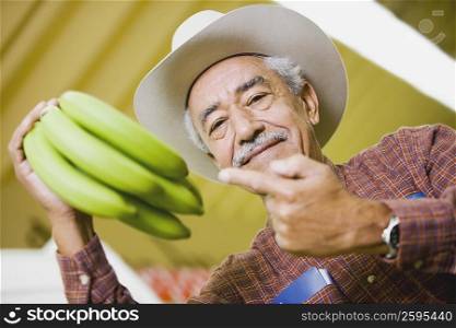 Low angle view of a senior man holding a bunch of bananas