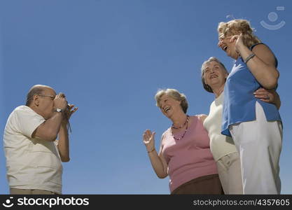 Low angle view of a senior man photographing of three senior women