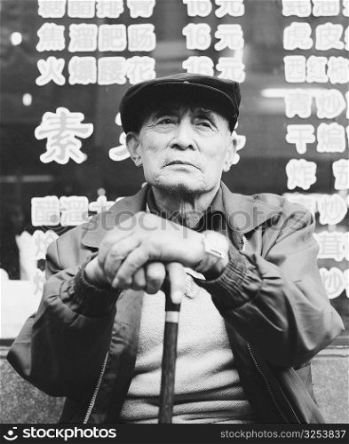 Low angle view of a senior man sitting and holding a cane
