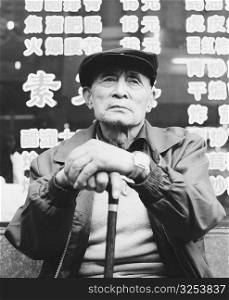 Low angle view of a senior man sitting and holding a cane