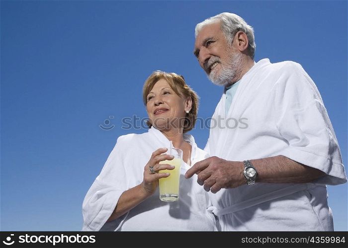 Low angle view of a senior woman holding a glass of juice and standing with a senior man