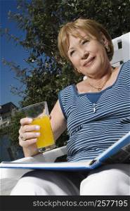Low angle view of a senior woman sitting on a chair and drinking juice