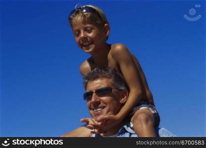 Low angle view of a son sitting on his father&acute;s shoulders