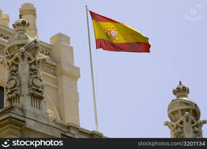 Low angle view of a Spanish flag fluttering on a building, Madrid, Spain