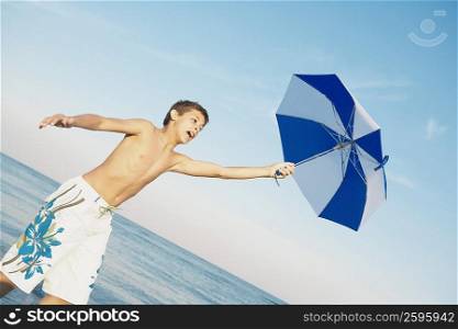 Low angle view of a teenage boy holding an umbrella