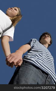Low angle view of a teenage boy holding hand of his sister