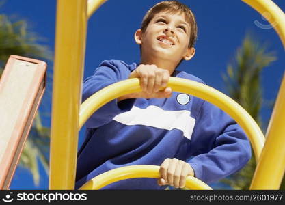 Low angle view of a teenage boy on a jungle gym