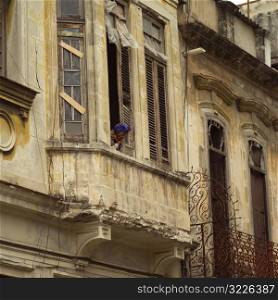 Low angle view of a woman looking out from a window of a building, Havana, Cuba