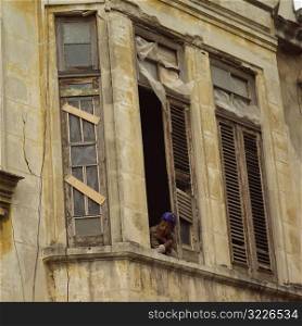 Low angle view of a woman looking out of a window of a building, Havana, Cuba