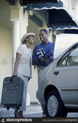 Low angle view of a young couple packing luggage into a car