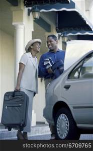 Low angle view of a young couple packing luggage into a car