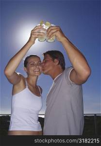 Low angle view of a young couple toasting with drinks