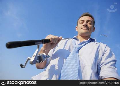 Low angle view of a young man holding a fishing rod