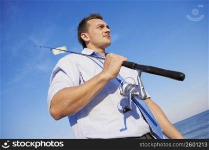 Low angle view of a young man holding a fishing rod