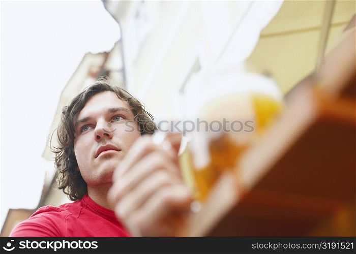Low angle view of a young man holding a glass of beer