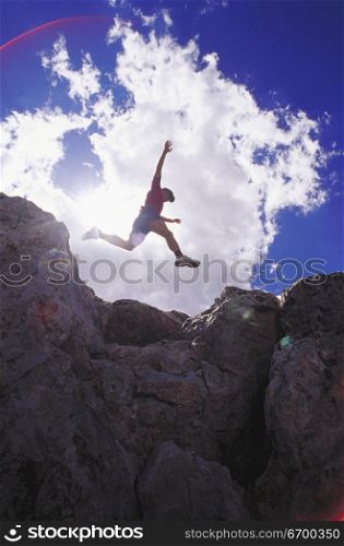 Low angle view of a young man jumping on rocks