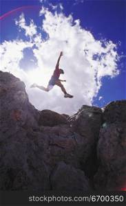 Low angle view of a young man jumping on rocks