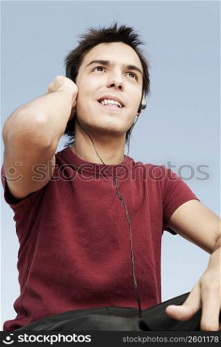Low angle view of a young man listening to music