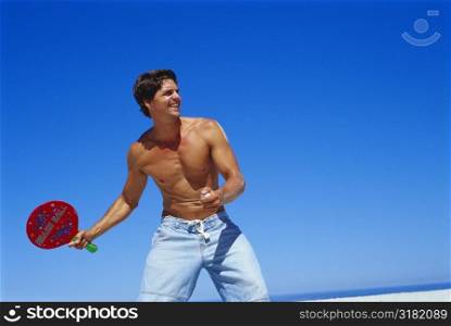 Low angle view of a young man playing table tennis on the beach