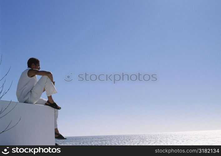 Low angle view of a young man sitting on a wall