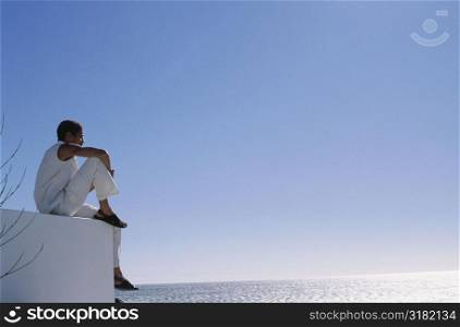 Low angle view of a young man sitting on a wall
