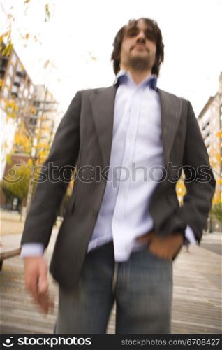 Low angle view of a young man standing with his hand in his pocket