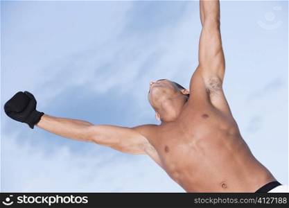 Low angle view of a young man with his arms raised