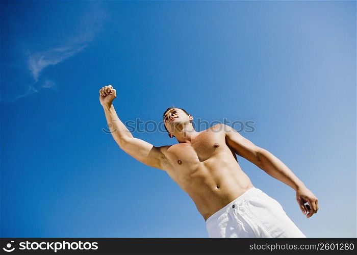 Low angle view of a young man with his hand raised