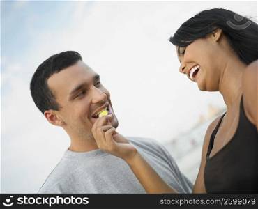 Low angle view of a young woman feeding a potato chip to a young man